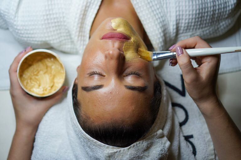 Woman receiving natural turmeric facial mask application during spa treatment