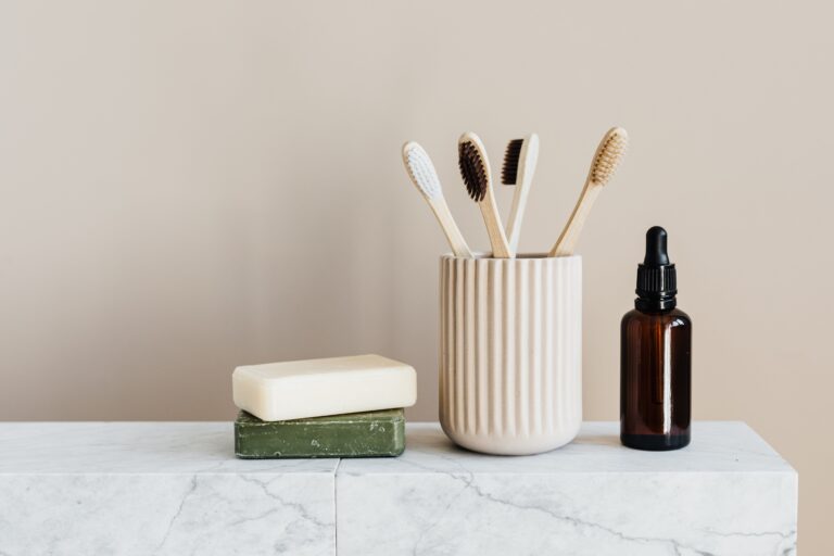 Display of two organic soap bars, toothbrushes in a cup and an essential oil