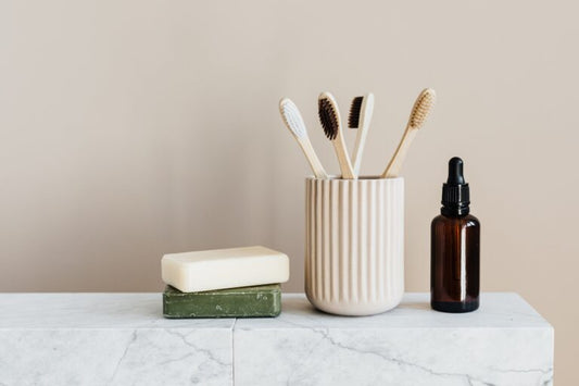 Display of two organic soap bars, toothbrushes in a cup and an essential oil